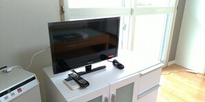 Relax in this stylish living room with a flat-screen TV, comfortable seating, and a window with blinds.