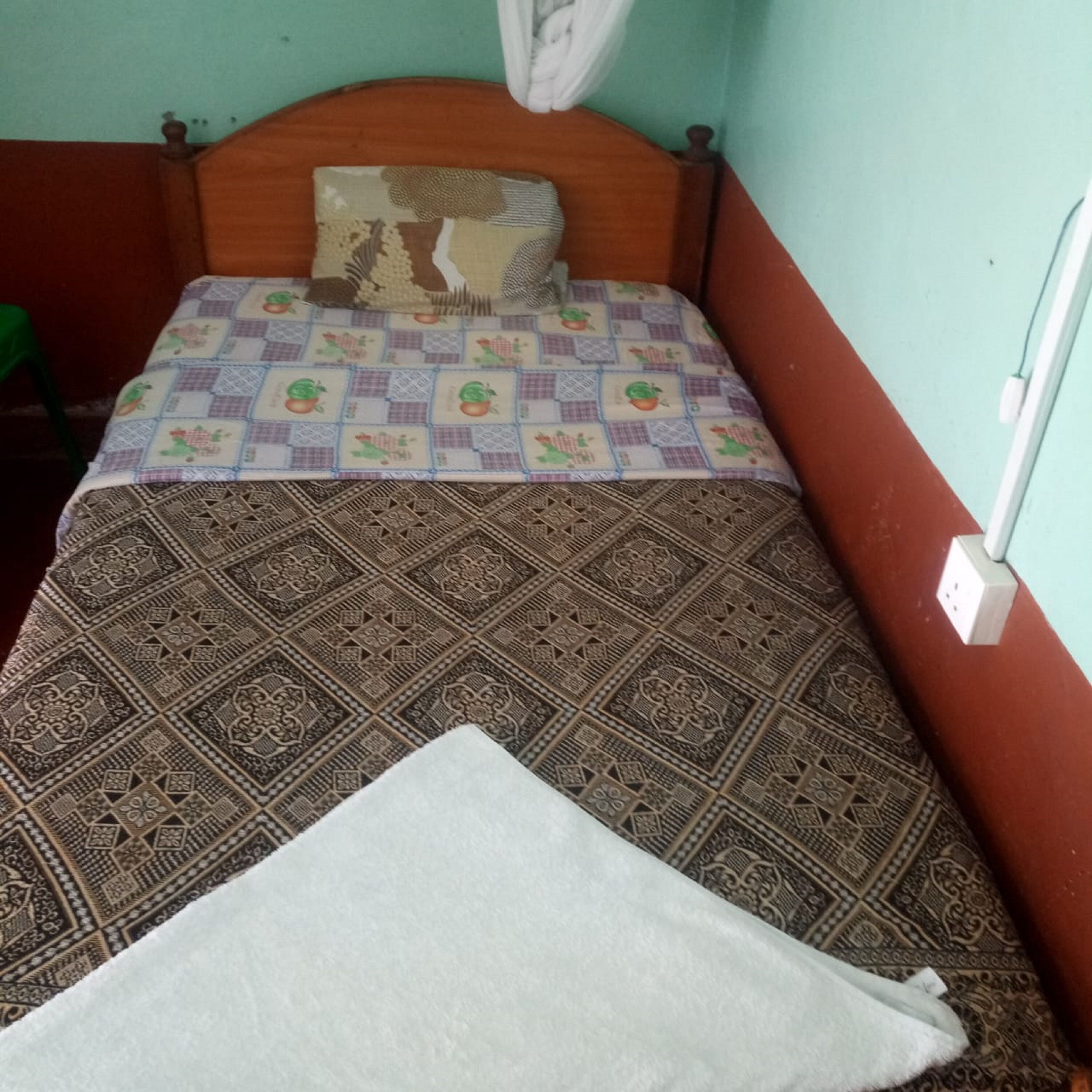 A bed with a patterned bedspread, a pillow, and a white blanket.