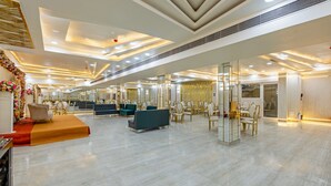 Un hall d’entrée spacieux, doté d’un plafond haut, d’un éclairage moderne et d’un espace de détente central avec des canapés et des fauteuils.
