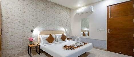 A hotel room with a bed, a nightstand, a mirror, a ceiling fan, and a wooden door.