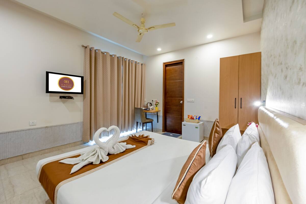 A hotel room with a bed, a desk, a chair, a wardrobe, and a television.