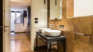 Une salle de bain moderne avec deux vasques, un meuble-lavabo foncé et un grand miroir.