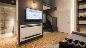 Un salon moderne avec un téléviseur à écran plat fixé au mur, un escalier et une porte.