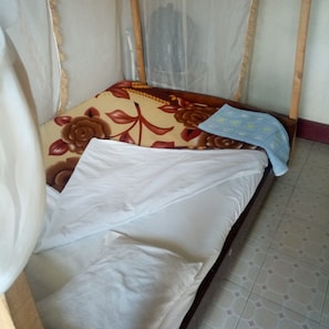 Uma cama de solteiro com colcha florida, travesseiro branco e manta azul.
