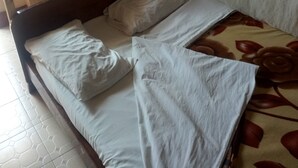 A single bed with white bedding, a wooden headboard, and a floral-patterned bedspread. - Kibiro Lodge (Naivasha)