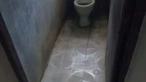 A narrow hallway with a toilet at the end. - Kibiro Lodge (Naivasha)