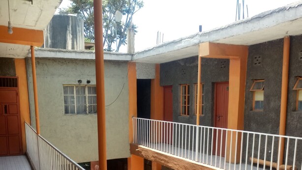 A multi-level building with balconies and a fire exit sign. - Kibiro Lodge (Naivasha)