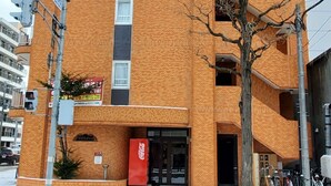 A tall brick building with multiple balconies, a Coca-Cola vending machine, and a Coca-Cola sign outside. - PEOPLE NoIII 601 (Sapporo)