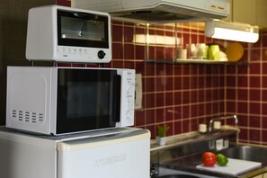 A kitchen with a microwave and toaster oven stacked on top of a refrigerator.