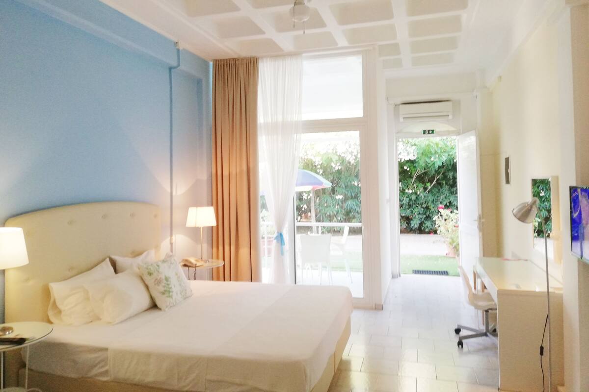 A hotel room with a bed, a desk, and a view of the outdoors.