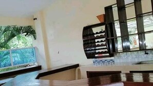 Un área de cocina con encimera de piedra, pileta integrada y ventana con vista a follaje.