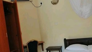 Un dormitorio con una cama, una silla, una mesita y un armario.