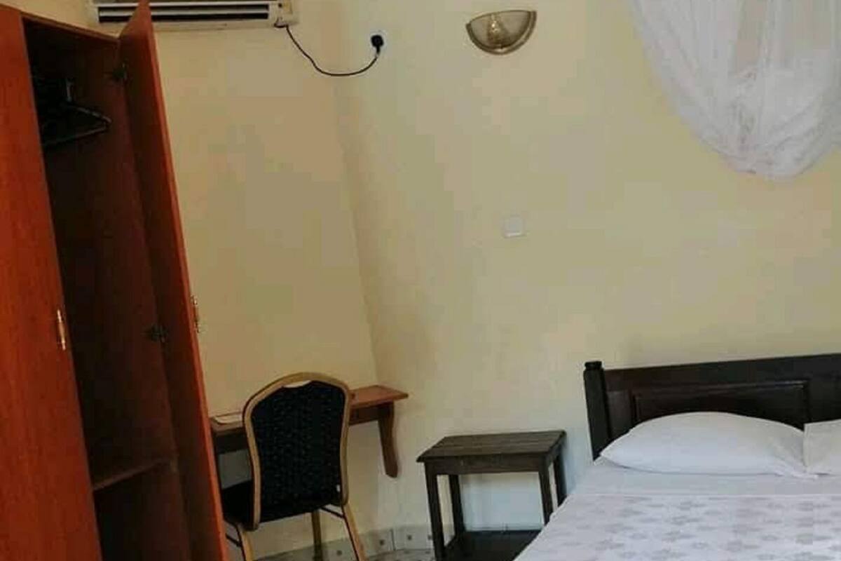 A bedroom with a bed, a chair, a small table, and a wardrobe.