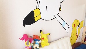 A white sofa with a tufted backrest and a wall with a large cartoon character. - PEOPLE NoIII 810 (Sapporo)
