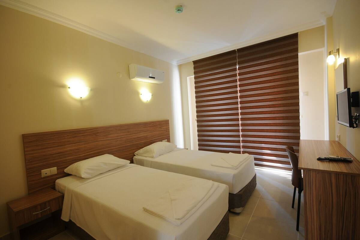 Ein Hotelzimmer mit zwei Betten, einem Schreibtisch und einem Fernseher.