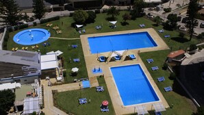 Ett flygbildsfoto av ett semesterområde med två stora pooler, solstolar och en liten, rund pool.