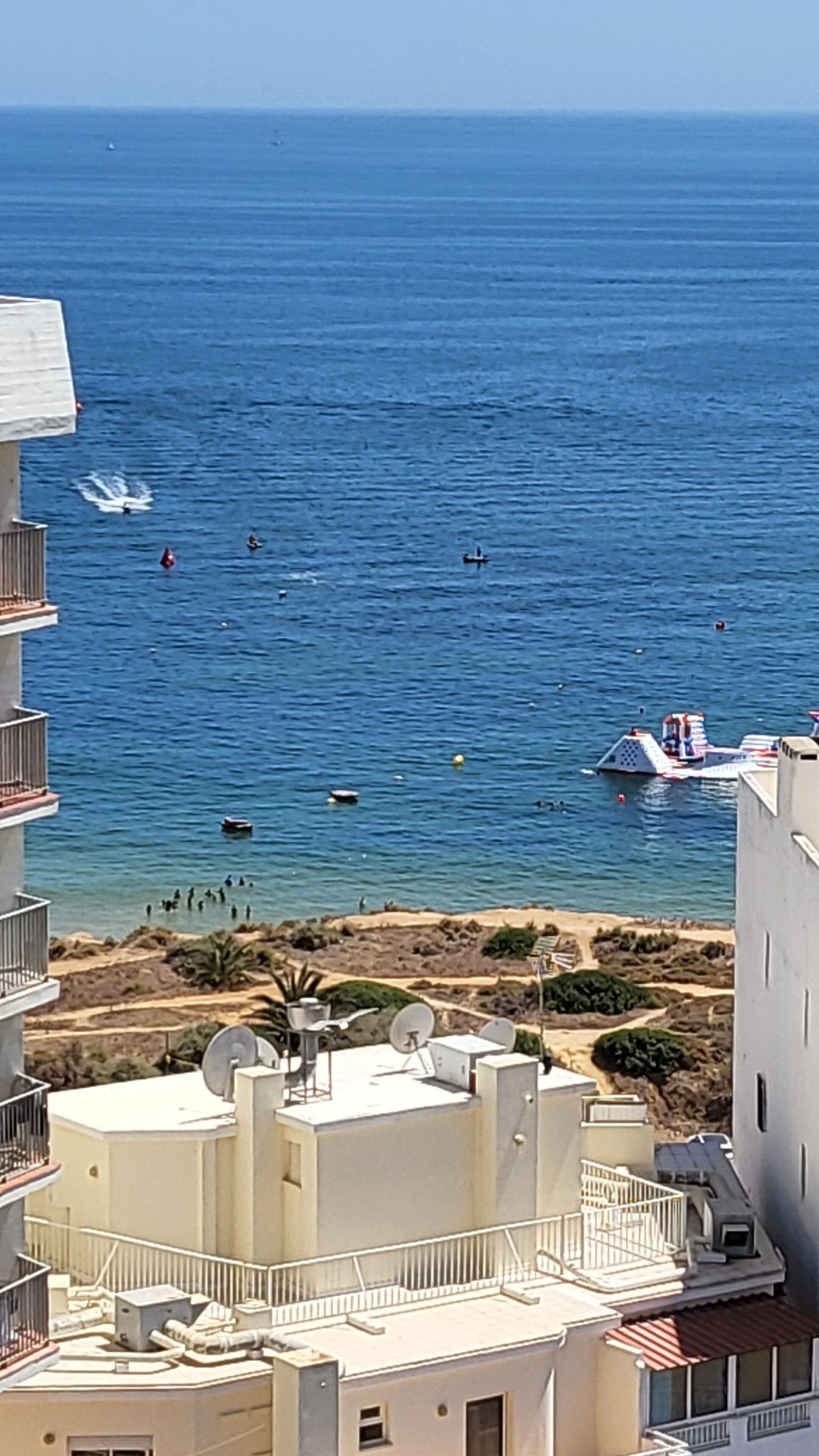 A coastal view with a beach, boats, and buildings.