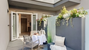 An outdoor seating area with a table and chairs, a bench, and a decorative wall with plants. - Romagna Suite Hotel (Gatteo)