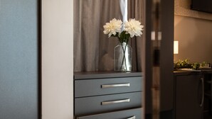 A modern kitchen with a dark countertop, a vase with white flowers, and a cabinet with drawers. - Romagna Suite Hotel (Gatteo)