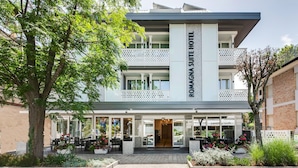 A modern hotel with a prominent entrance, outdoor seating, and a well-maintained garden area. - Romagna Suite Hotel (Gatteo)