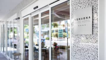 De gevel van Romagna Suite Hotel, met een glazen ingang, terras en een bord.