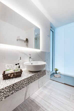 A modern bathroom with a large white sink, marble backsplash, and a small window with a view. - Romagna Suite Hotel (Gatteo)
