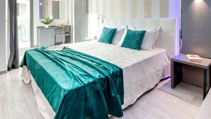 A modern bedroom with a large bed, a desk, and a chair. - Romagna Suite Hotel (Gatteo)