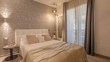 A bedroom with a large bed, a bedside table with a lamp, a mirror, and a window with curtains.