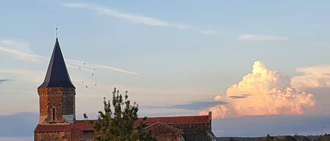Una iglesia con una torre destacada y una nube grande y esponjosa en el cielo.