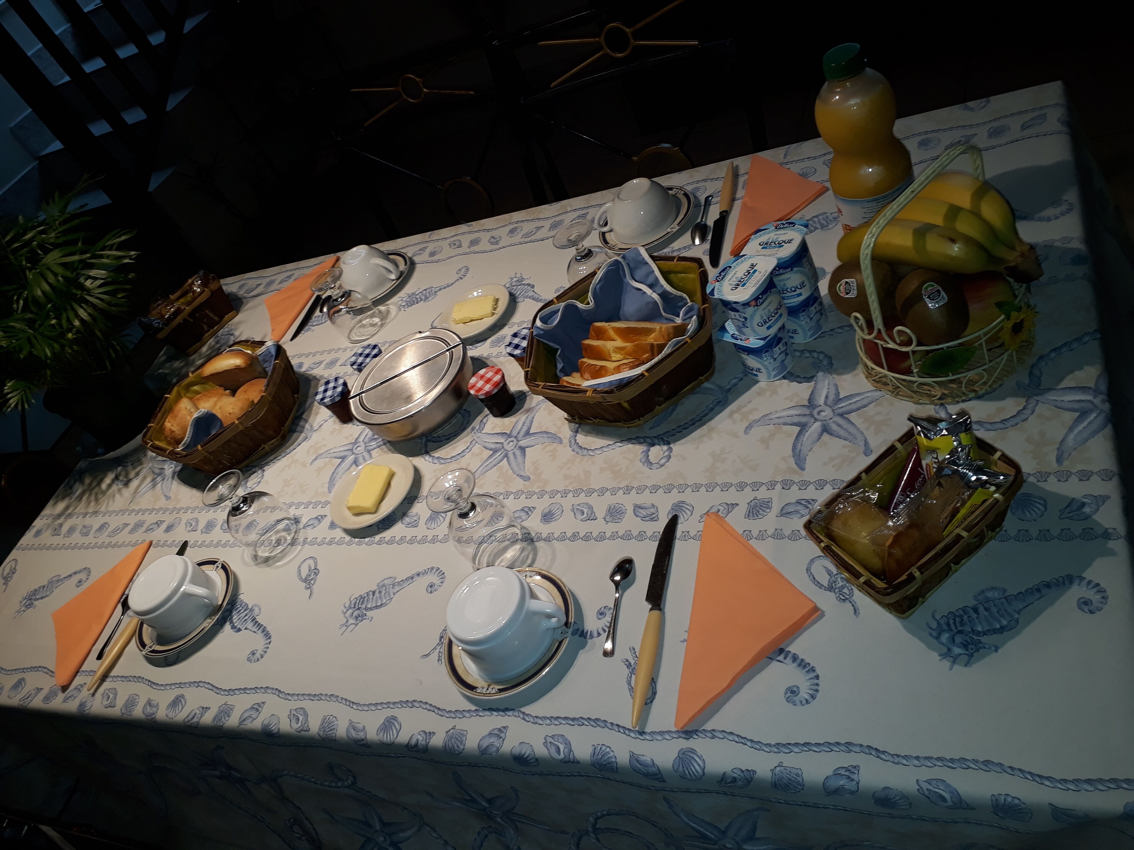 Mesa posta com diversos itens de café da manhã, incluindo pão, manteiga e suco de laranja.