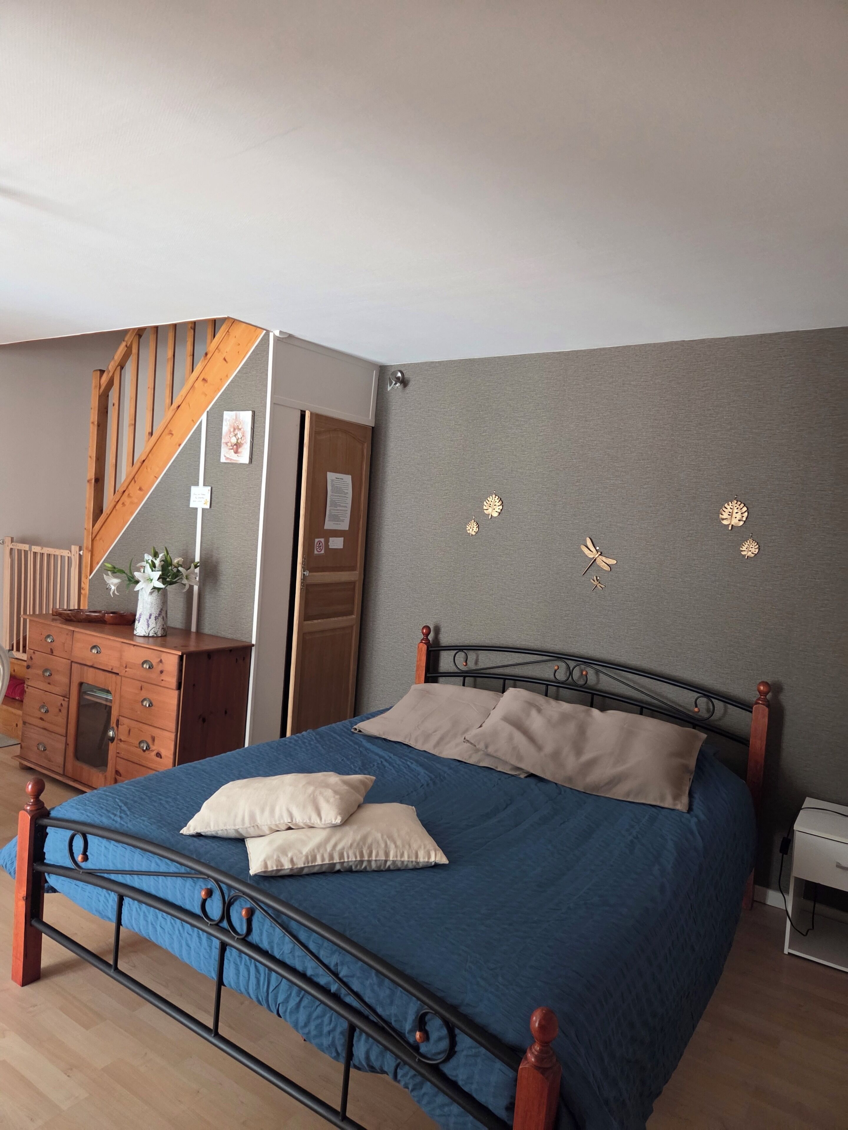 A bedroom with a bed, dresser, and a wooden staircase.