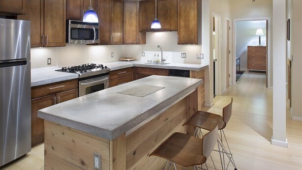 A modern kitchen with wooden cabinets, stainless steel appliances, and a central island with bar stools. - Downtown Carbondale Retreat Next to Sopris Park, Walkable & Dog-Friendly (Carbondale)