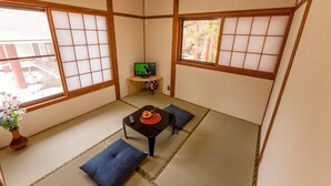 A traditional Japanese room with tatami flooring, shoji screens, a small table with a red tray, and a green screen. - kongoji syukubo seihoin (Azumino)
