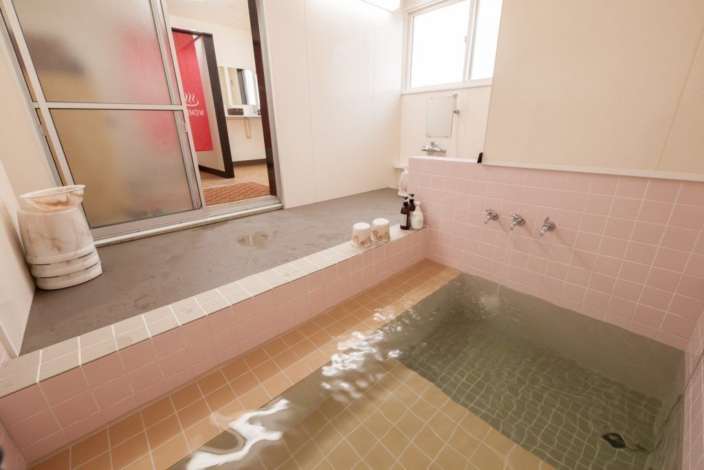 A bathroom with a bathtub, a mirror, and a window.