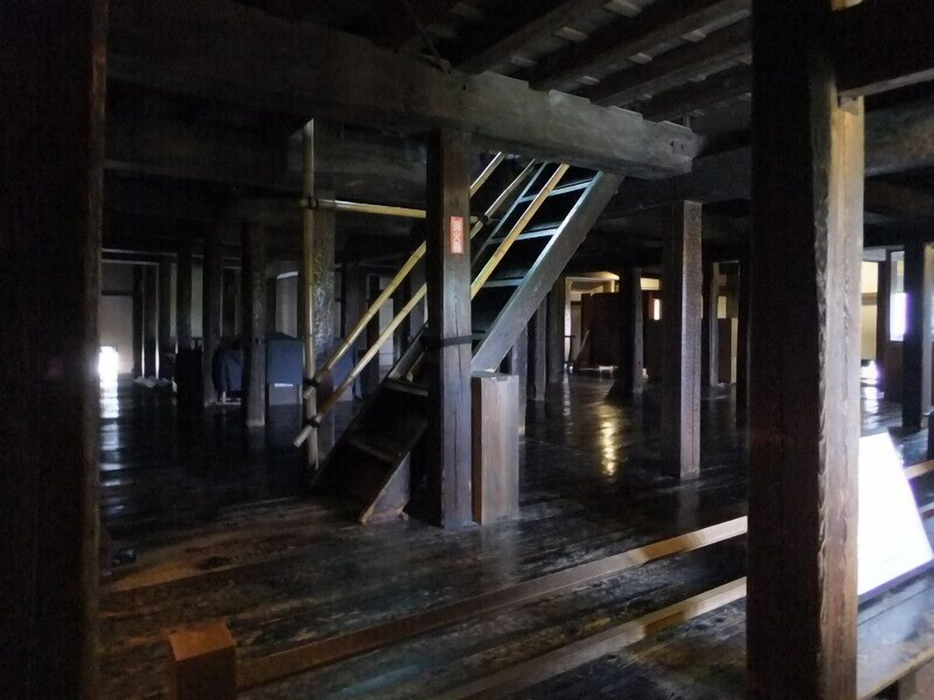 Interior com escada, vigas de madeira e piso polido.