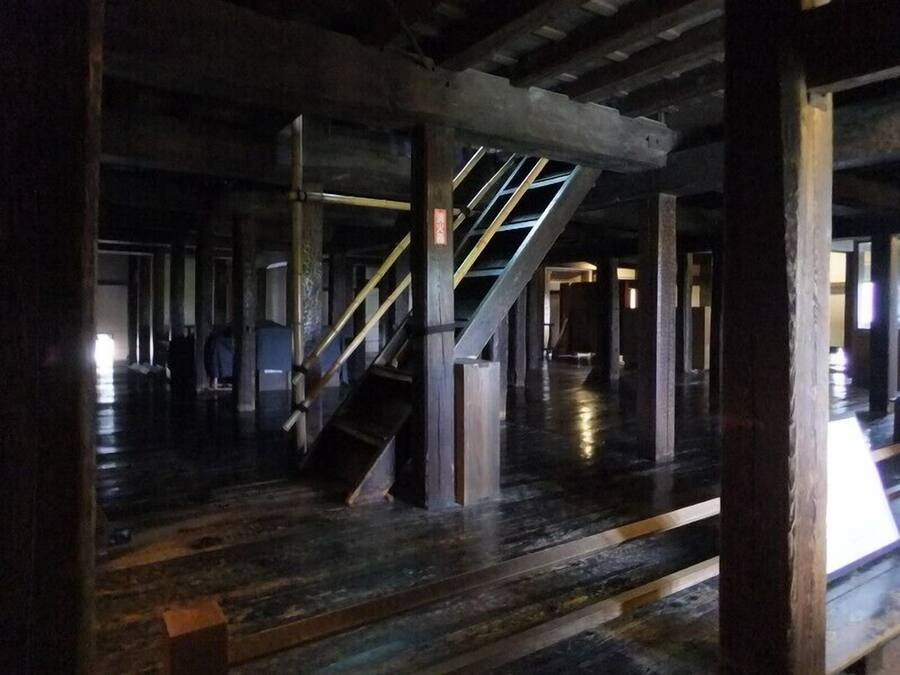 Interior com escada, vigas de madeira e piso polido.