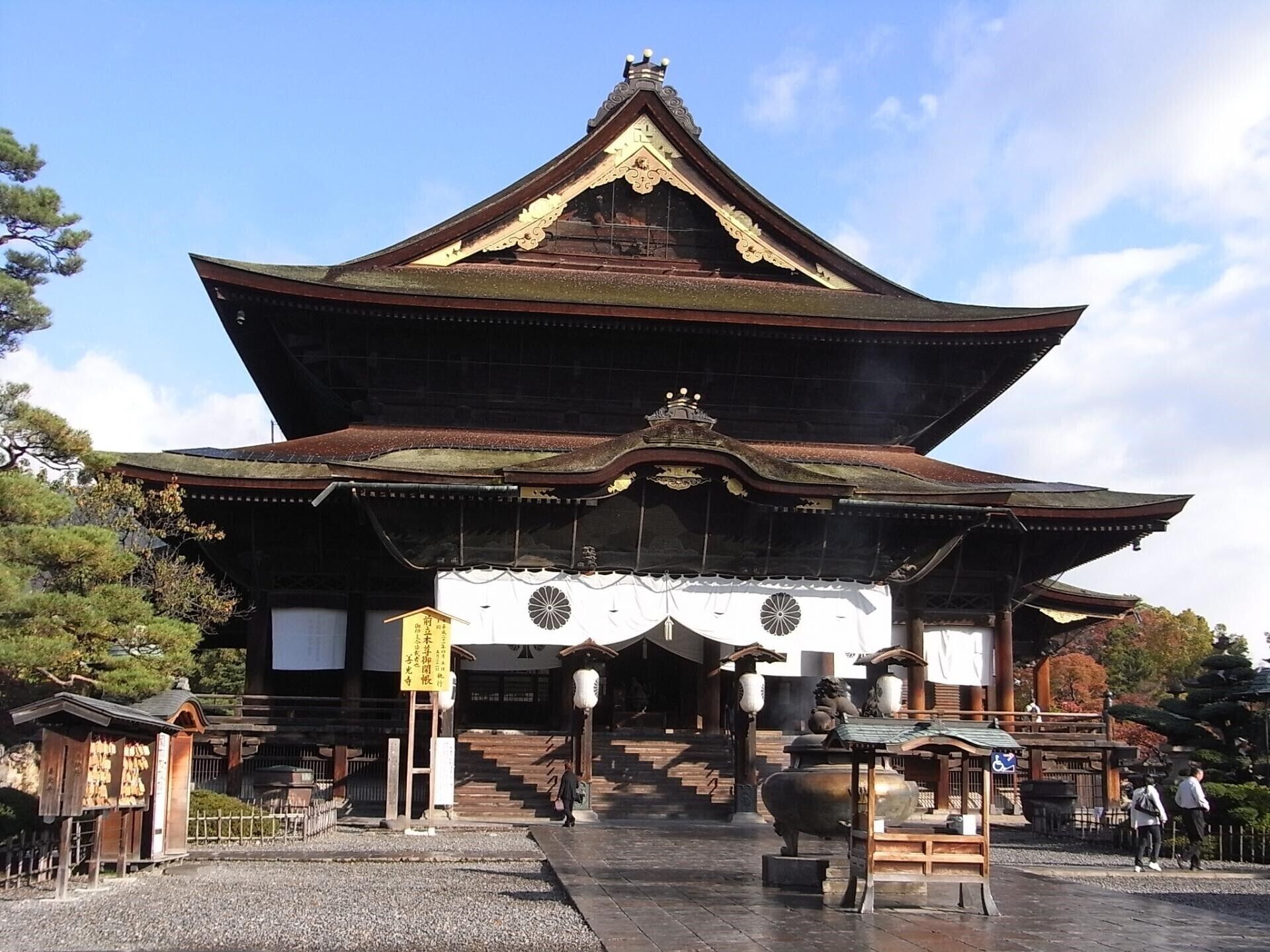 Um templo japonês tradicional com uma entrada grande e ornamentada e uma escadaria que leva até o edifício principal.