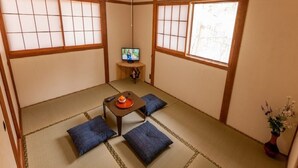A traditional Japanese room with tatami flooring, a low table with cushions, a television, and a window with wooden frames. - kongoji syukubo seihoin (Azumino)