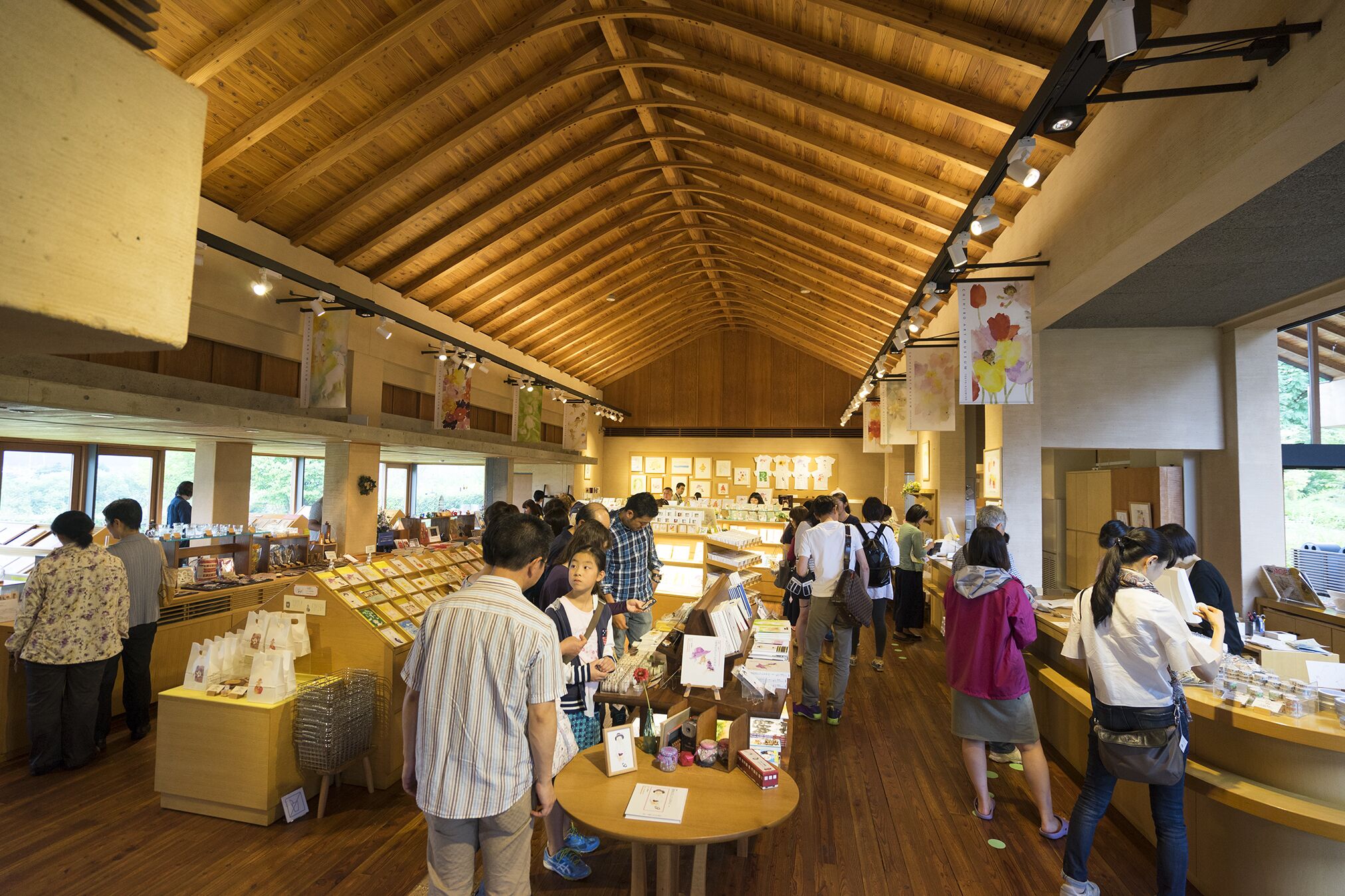 A bookstore with wooden floors and a high ceiling, featuring bookshelves and tables for browsing.