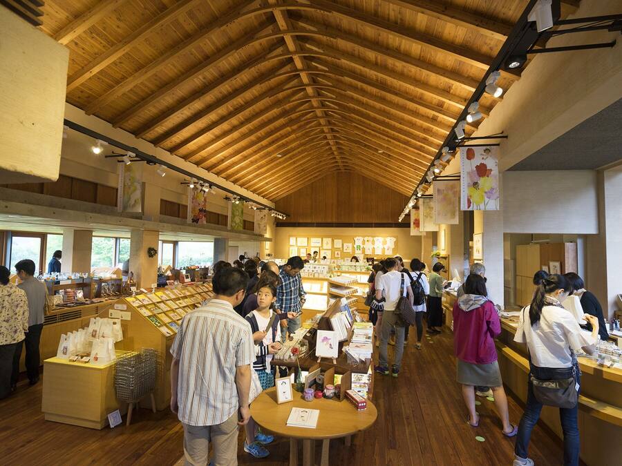 A bookstore with wooden floors and a high ceiling, featuring bookshelves and tables for browsing.