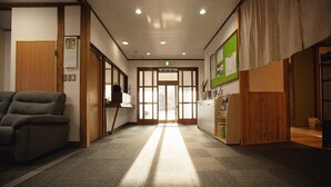 A hotel lobby with a reception desk, a sofa, and a wooden partition. - kongoji syukubo seihoin (Azumino)