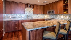 Una cocina moderna con armarios de madera, una isla de mármol y un microondas de acero inoxidable.