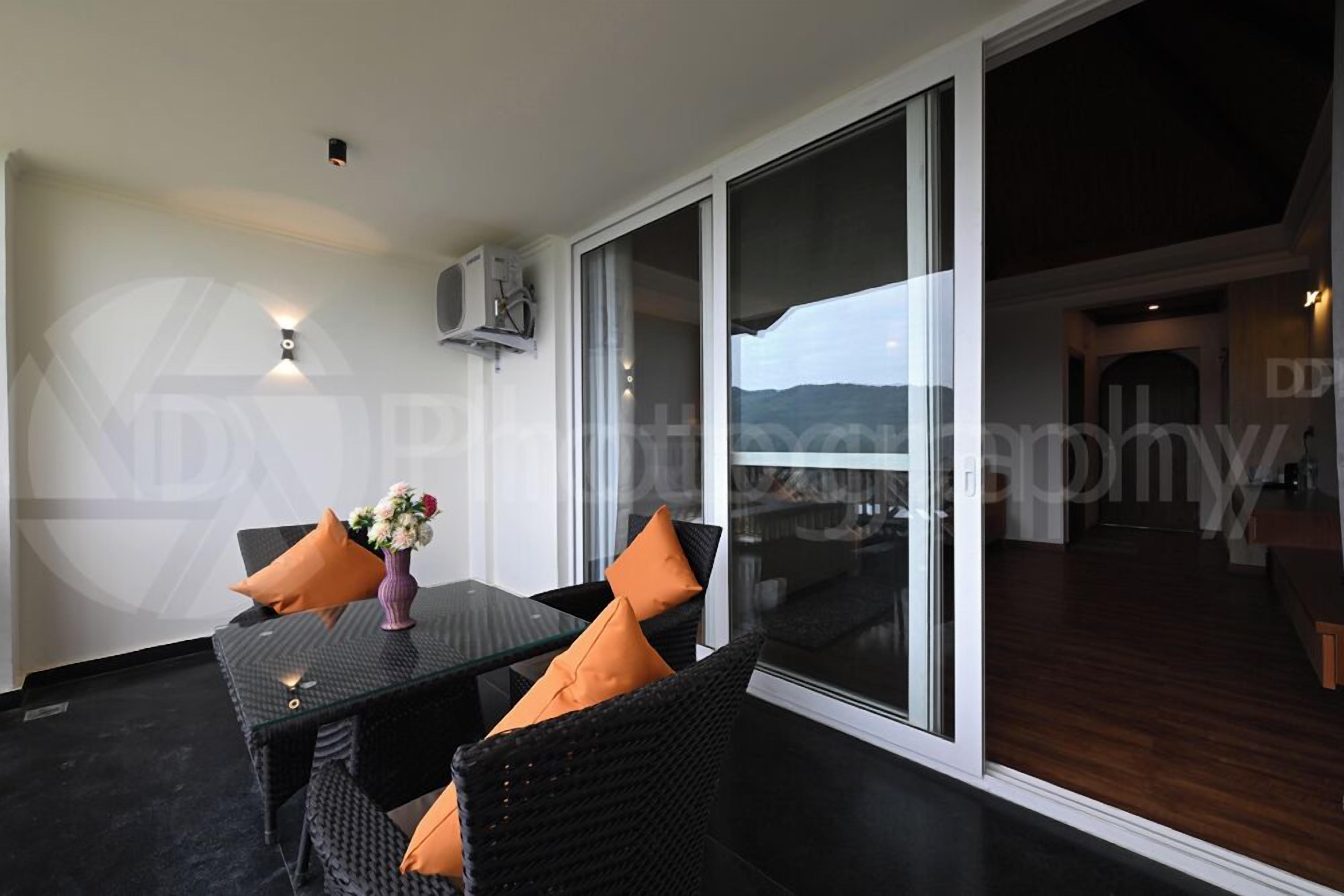 A balcony with a glass door, a table with chairs, and a vase of flowers.