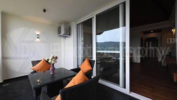 A balcony with a glass door, a table with chairs, and a vase of flowers.
