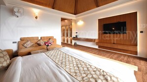 Een moderne slaapkamer met een groot bed, houten plafond, een ingebouwde televisie en een inloopkast.