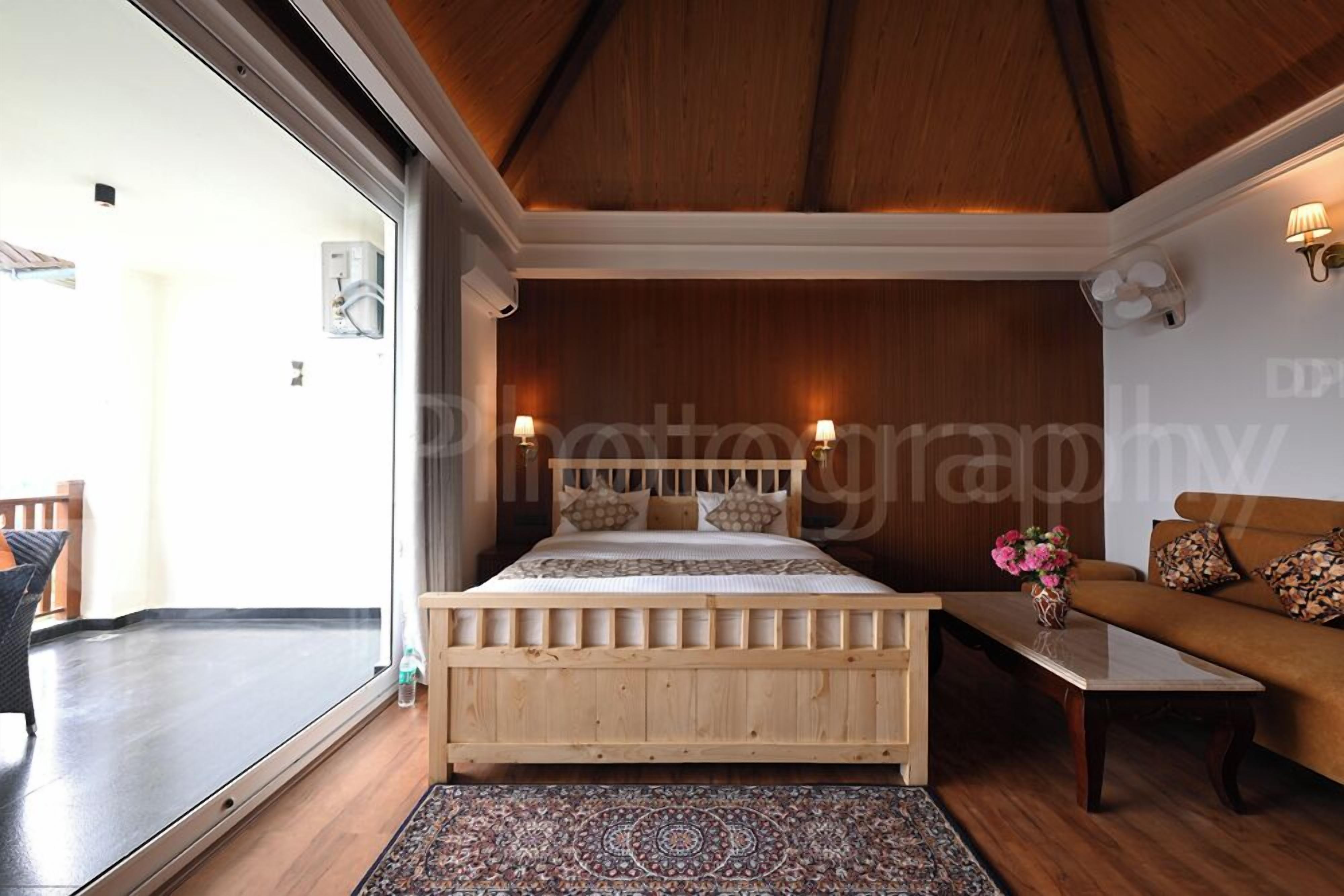 Ein Schlafzimmer mit einem hölzernen Bett, einem Sofa, einem Couchtisch und einem gemusterten Teppich.