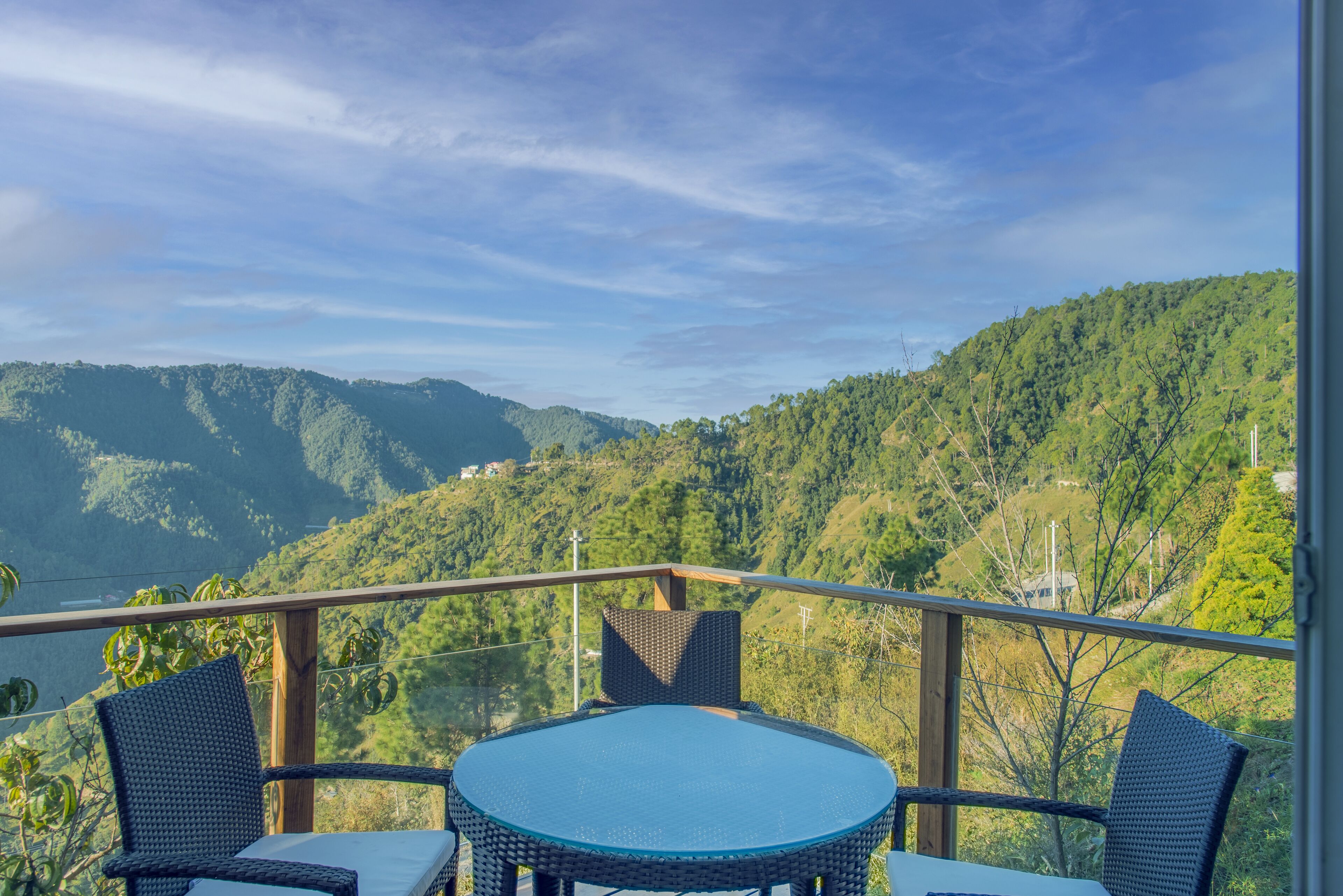 A balcony with a round table and two chairs, overlooking a mountainous landscape.