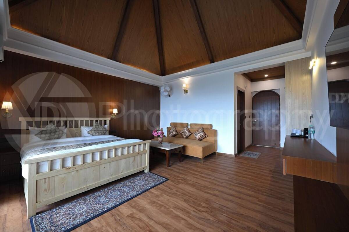 A bedroom with a wooden bed, a sofa, a small table, and a nightstand.