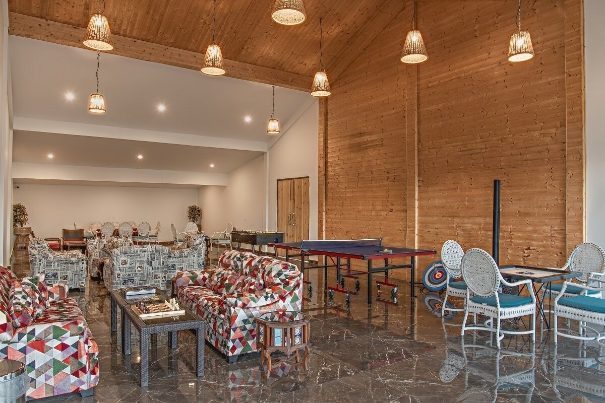 A spacious lounge area with a billiards setup, comfortable seating, and a polished marble floor.