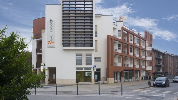 A modern building with a white facade and a central vertical section with horizontal slats.
